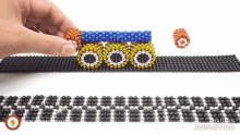 a person is playing with a bracelet made of beads that says made in animatica