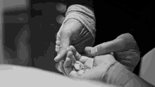a black and white photo of a person holding another person 's hand and a necklace