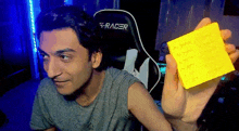 a man is holding a yellow sticky note with writing on it .