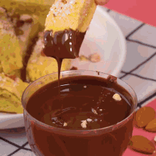 a person dipping a piece of food in a bowl of chocolate sauce