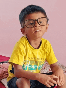 a young boy wearing glasses and a yellow authentication shirt