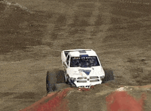 a monster truck is doing a trick on a dirt track in front of a banner that says wireless for all