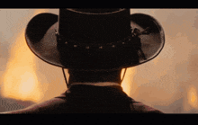 a man in a cowboy hat stands in front of flames