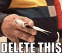 a man is holding a piece of paper in his hand with the words `` delete this '' written on it .