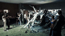 a group of people are standing in a room looking at a painting that is being destroyed