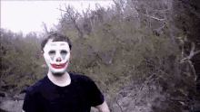 a man wearing a clown mask is standing in a forest