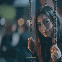 a woman is crying while sitting on a chain swing