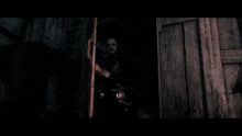 a man in a black coat is holding a gun in a dark room