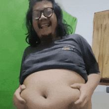 a man with glasses and a beard is holding his belly with both hands