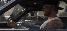 a man wearing sunglasses and a hat is driving his car