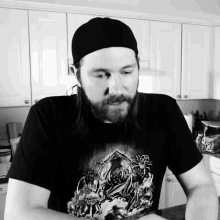 a man with a beard is wearing a black t-shirt with a picture of a castle on it