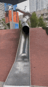 a metal slide is going down a hill in a city park