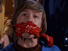 a man with a red bandana around his neck has the letter m on it