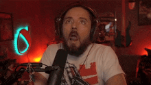 a man with a beard wearing headphones is sitting in front of a microphone and making a funny face .