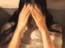 a woman is covering her face with her hands in a blurry photo .