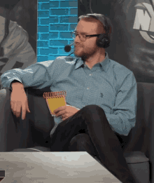 a man wearing headphones is sitting on a couch and holding a notebook