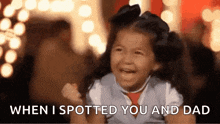 a little girl is smiling and laughing while holding her fist up .