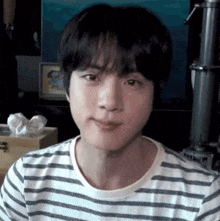 a close up of a person wearing a striped shirt making a face