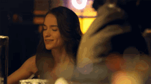 a woman sitting at a table with her eyes closed smiles