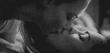 a black and white photo of a couple kissing .