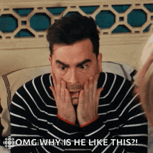 a man in a striped sweater has his hands on his face and says " omg why is he like this "