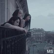 three women are standing on a balcony and the letters ms are on the bottom left