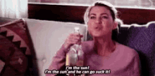 a woman is sitting on a couch drinking from a bottle and saying `` i 'm the sun ! ''