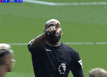 a soccer player wearing a black jersey with a lion on it points at the camera