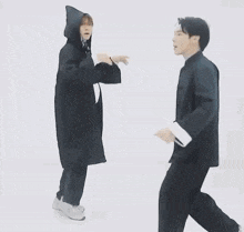 a man in a suit is dancing with another man in a yellow hat .