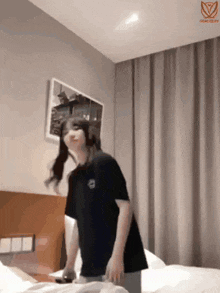 a woman in a black shirt is standing on a bed in a bedroom