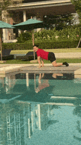 a man in a red shirt is kneeling next to a pool