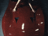 a woman laying on the hood of a red sports car