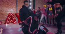 a group of people are dancing in front of a large red letter a