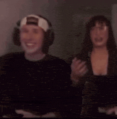 a man wearing headphones is covering his mouth while standing next to a woman