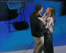 a man and a woman are dancing on a stage in front of a blue light .