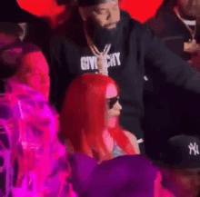 a woman with red hair is wearing sunglasses and a givenchy sweatshirt .