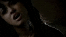 a close up of a woman 's face in a dark room with a blurred background .