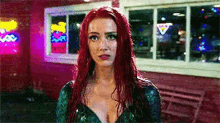 a woman with red hair is standing in front of a red building .
