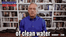 a man in a blue shirt stands in front of a bookshelf with the words of clean water written on it