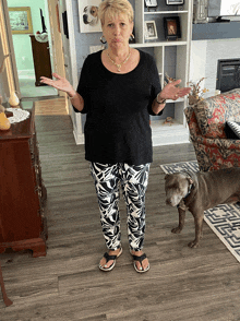 a woman standing in a living room with a dog standing next to her