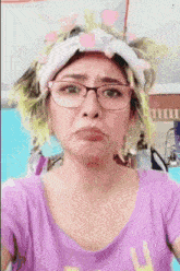 a woman wearing glasses and a headband is making a face