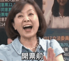 a woman in a blue shirt is laughing with her mouth open