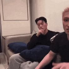 two men are sitting on a couch talking to each other in a living room .
