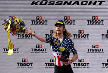 a man holding a trophy in front of a tissot banner