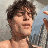 a young man with a piercing in his ear is standing in front of a window with his eyes closed .