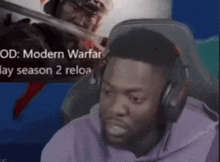 a man wearing headphones sits in front of a screen that says modern warfare day season 2 reload