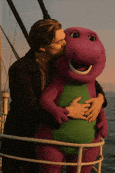a man is kissing a purple and green stuffed animal