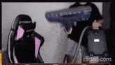 a man is holding a vacuum cleaner in front of a chair that says dxracer on it