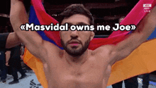 a shirtless man is holding a colorful flag with the words masvidal owns me joe written above him .