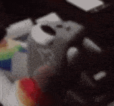 a blurred image of a person holding a remote control with a rainbow in the background